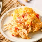 Scrambled eggs with cheese and tomatoes served on a white plate, breakfast recipe, healthy morning meal, delicious and flavorful egg dish, close-up of cheesy scrambled eggs with vegetables.