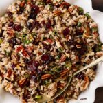 Savory wild rice salad with pecans, dried cranberries, and chopped green onions in a white serving dish. Perfect for healthy eating and holiday meals, packed with flavors and textures.