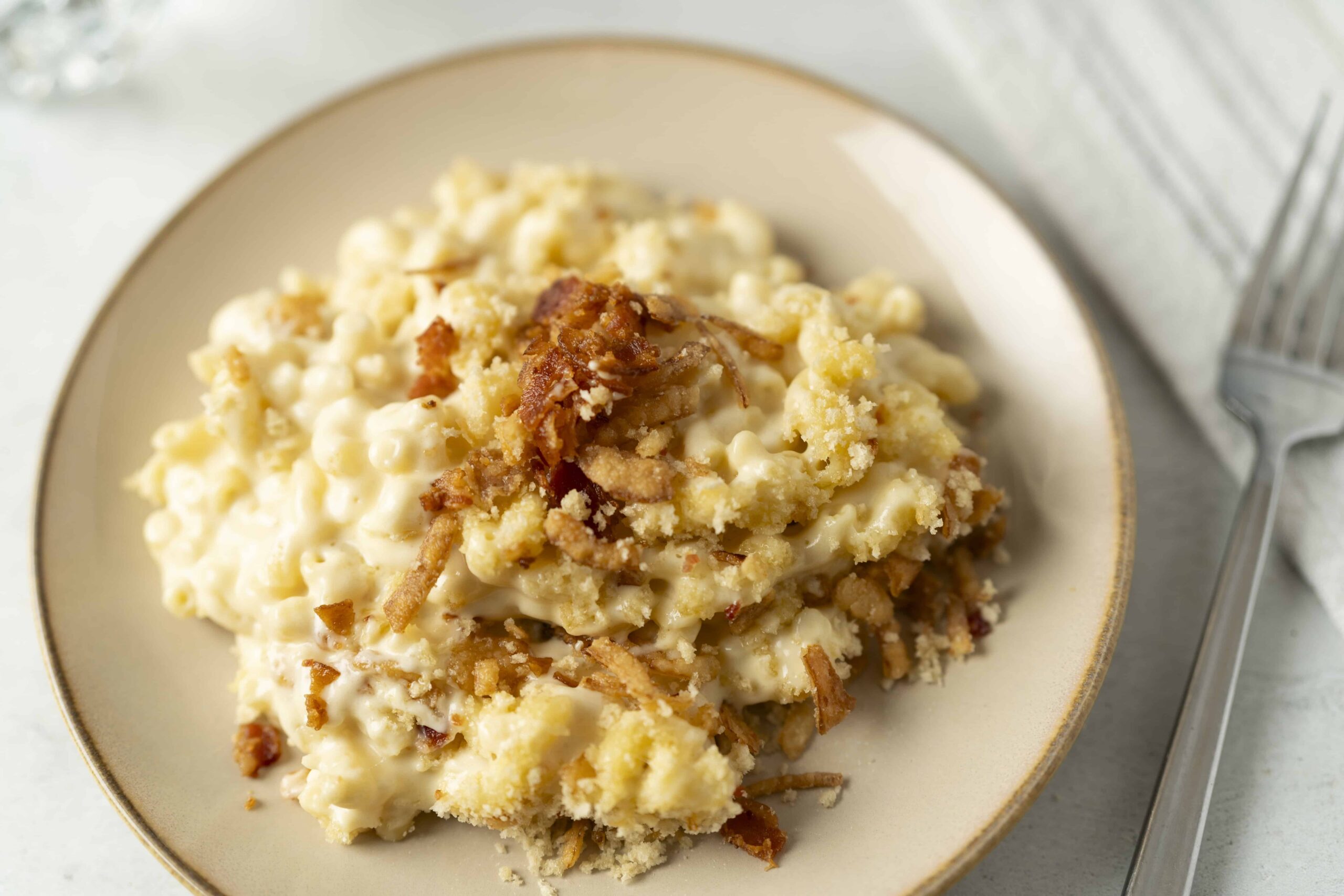 Creamy chicken casserole with crispy fried onions and breadcrumbs, served on a stylish beige plate, perfect for comforting home-cooked meals and family dinners.