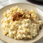Creamy macaroni and cheese topped with crispy bacon bits served on a beige plate, perfect comfort food for dinner or lunch.