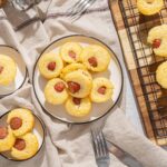 Soft cornbread muffins with spicy sausage filling on a rustic wooden tray, served on a linen cloth, perfect for breakfast or brunch.