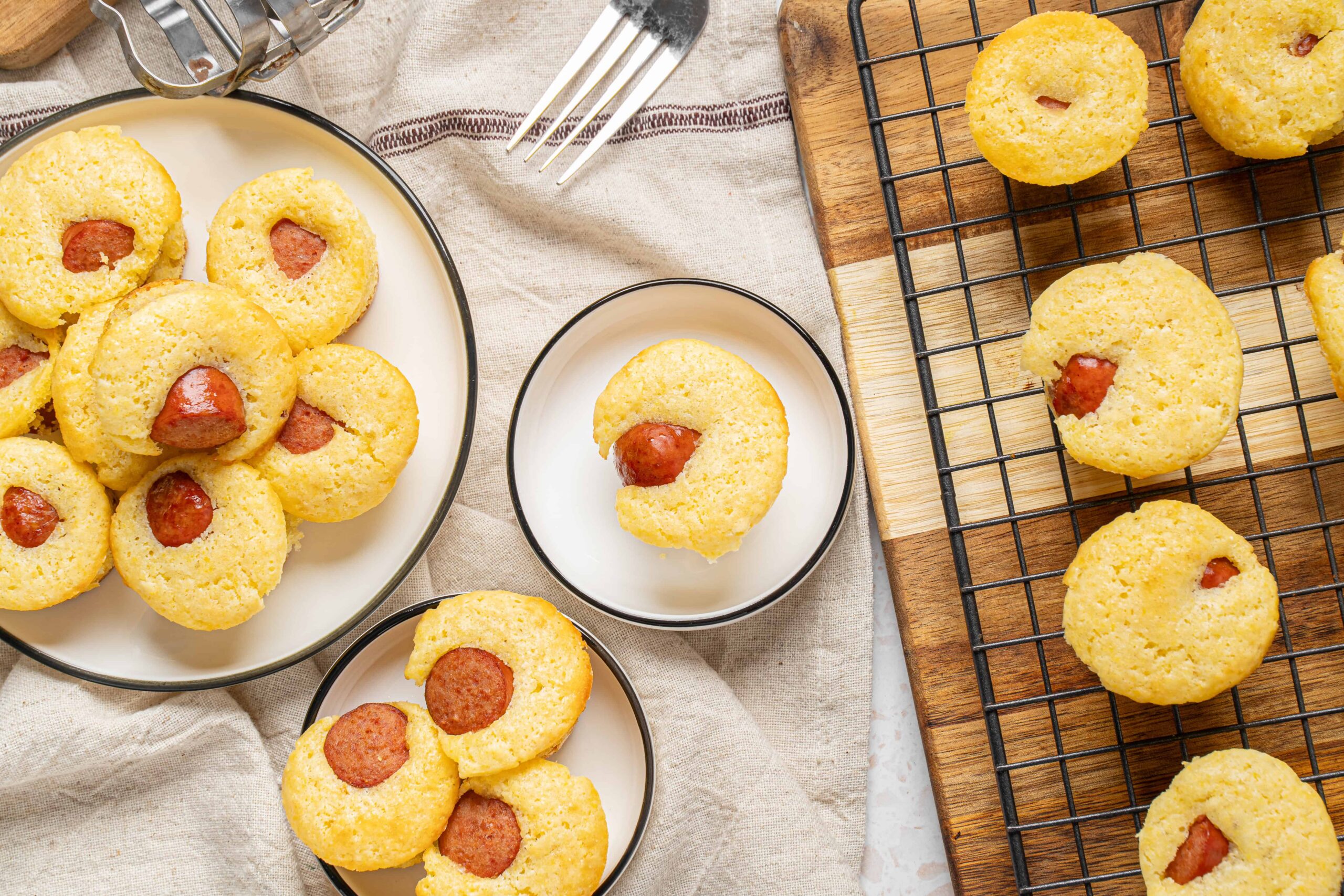 Cream cheese sausage mini muffins with hot dog filling, baked to golden perfection, served on plates and cooling rack. Perfect savory snack or appetizer, easy homemade recipe from Hey Recipe.