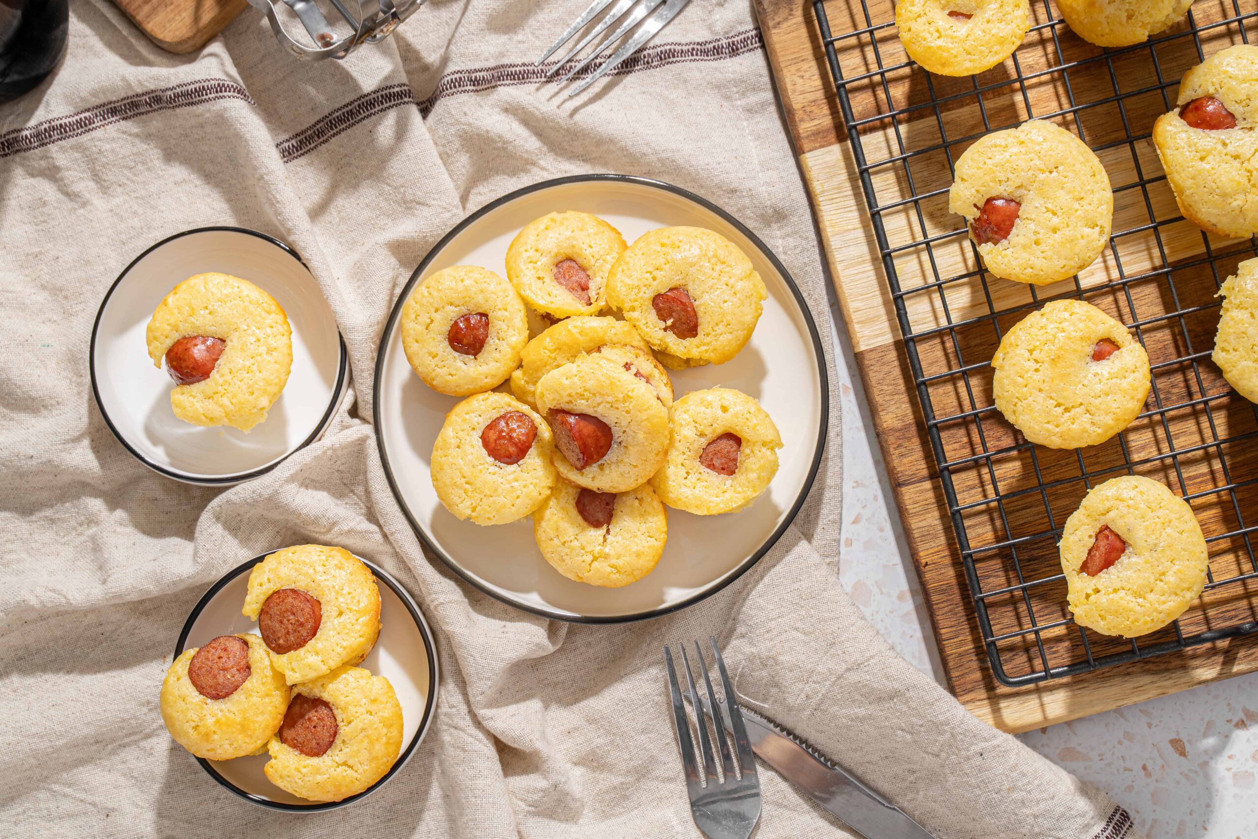 Soft cornbread muffins with spicy sausage filling on a rustic wooden tray, served on a linen cloth, perfect for breakfast or brunch.