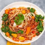 Savory spaghetti Bolognese with fresh basil, ground meat, vegetables, and rich tomato sauce on a white plate. Perfect for a hearty, flavorful Italian dinner.