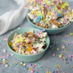 Colorful birthday popcorn mix with rainbow sprinkles, edible glitter, and candy in pastel bowls, perfect for festive celebrations and party snacks.