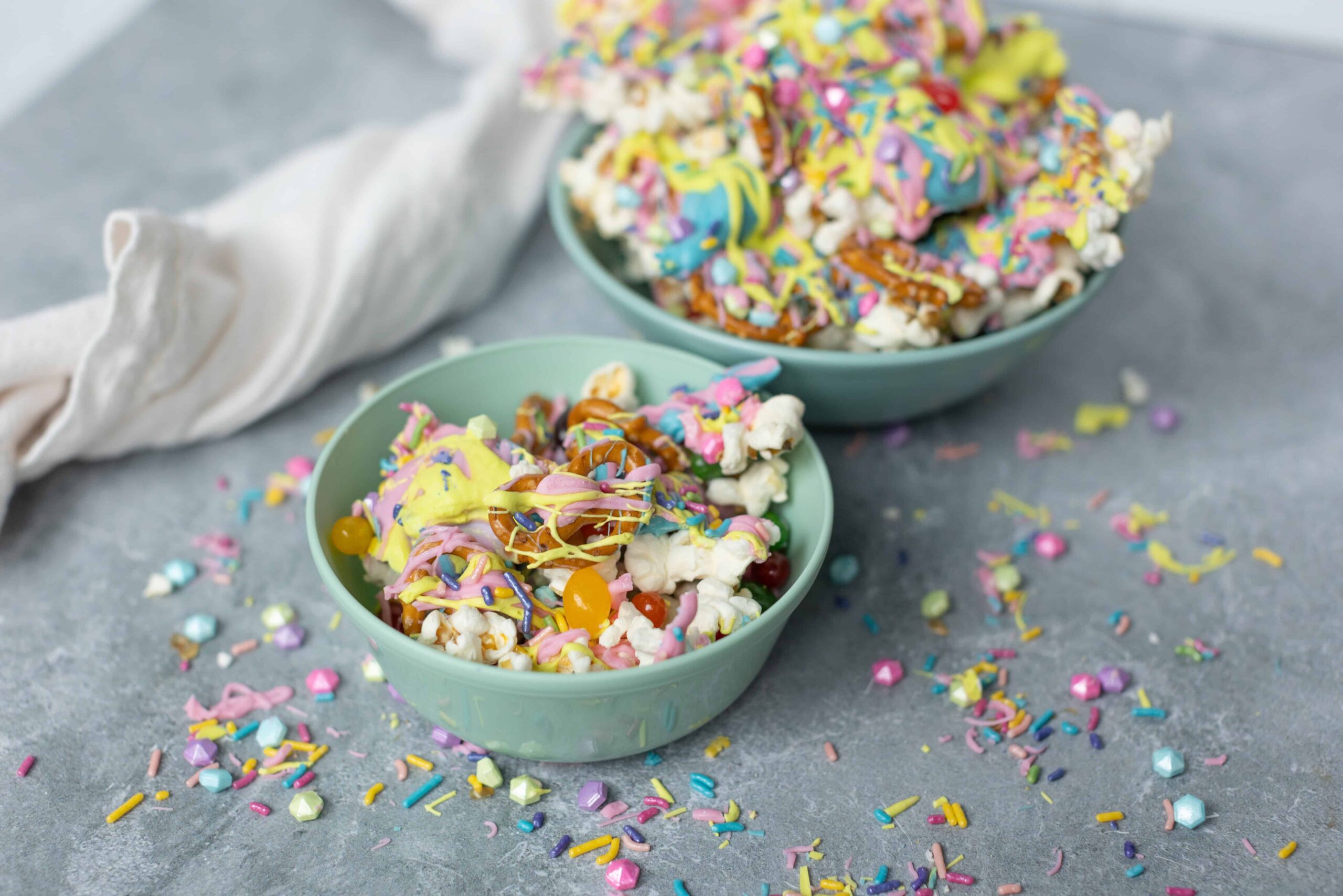 Colorful birthday popcorn mix with rainbow sprinkles, edible glitter, and candy in pastel bowls, perfect for festive celebrations and party snacks.