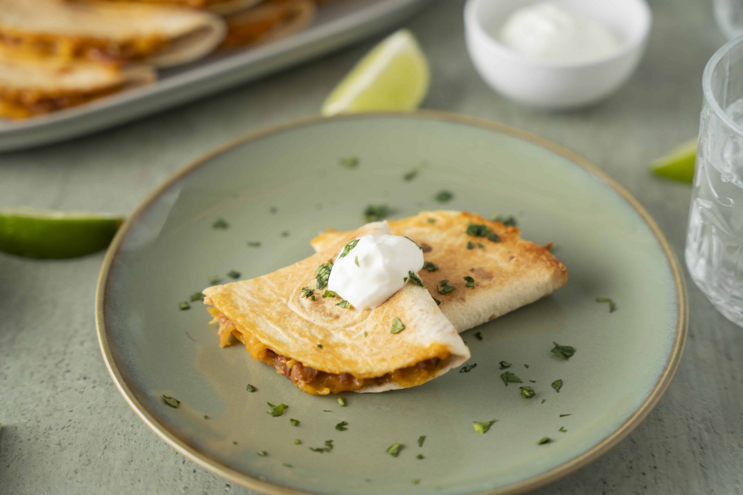Crispy beef burrito with melted cheese and sour cream on a green plate.