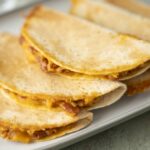 Cheesy beef quesadillas with golden crispy tortillas on a white rectangular plate. Perfect for a quick and delicious Mexican-inspired meal or snack.