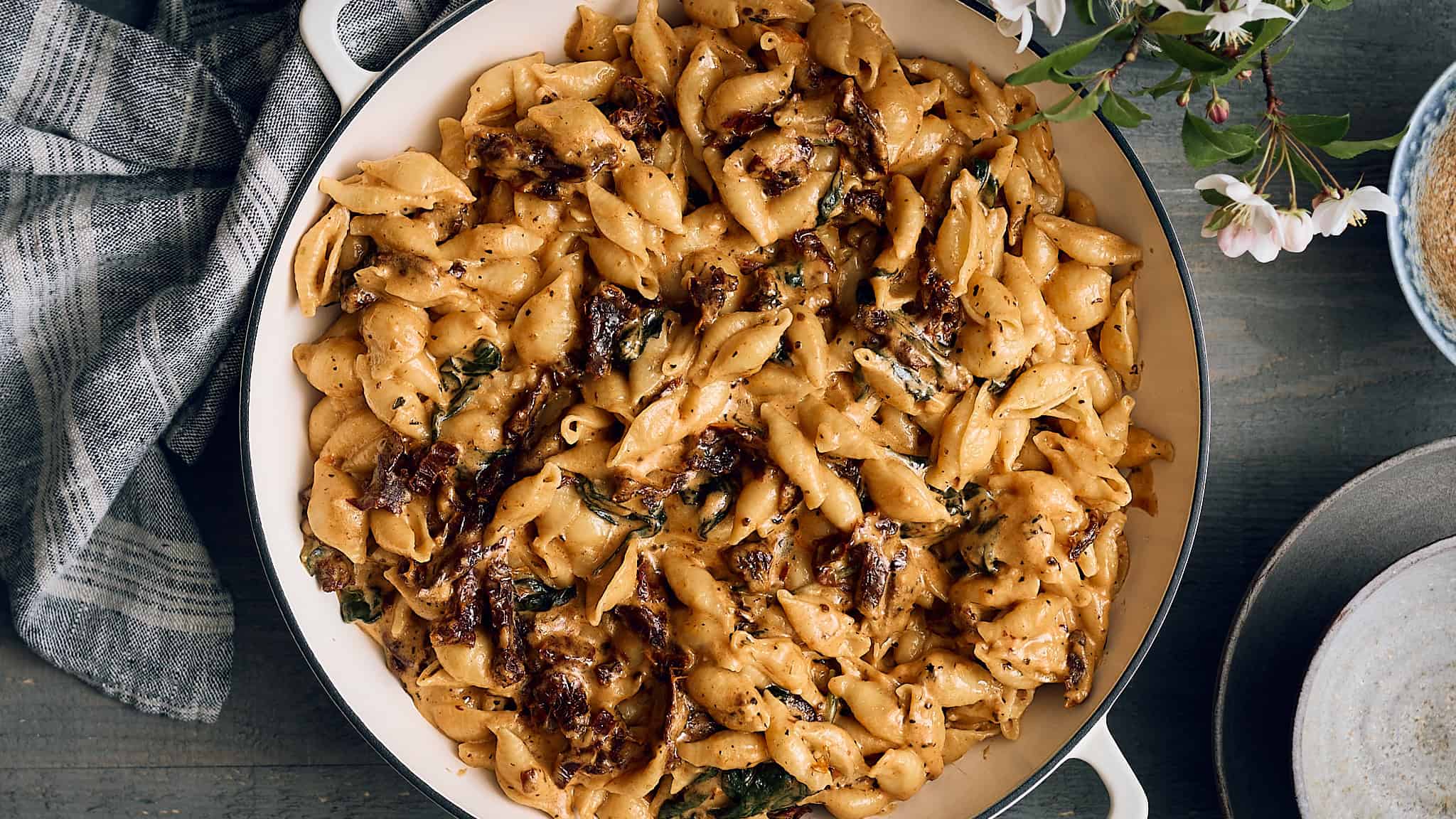 Creamy skillet pasta with caramelized onions and herbs, served in a white dish in a rustic setting.