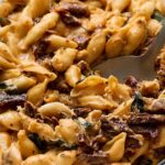 Creamy beef and spinach tortellini casserole in a white baking dish with a metal spoon for serving. Perfect comfort food recipe featuring cheese-filled pasta, tender beef, spinach, and creamy sauce.