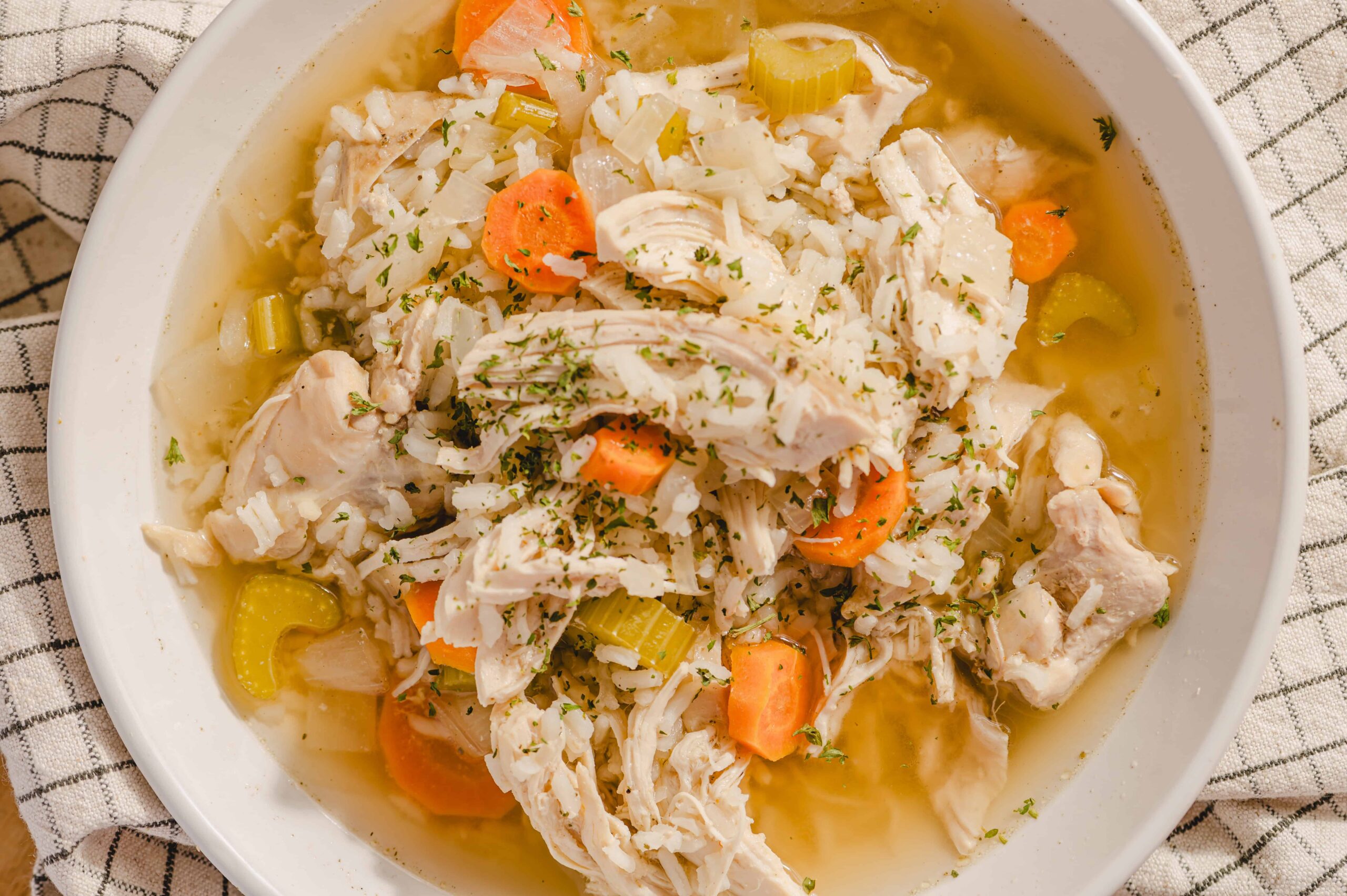 Savory chicken and vegetable soup, hearty homemade chicken noodle soup with carrots, celery, and herbs in a white bowl, healthy comfort food recipe, perfect for cold days and nutritious meals.