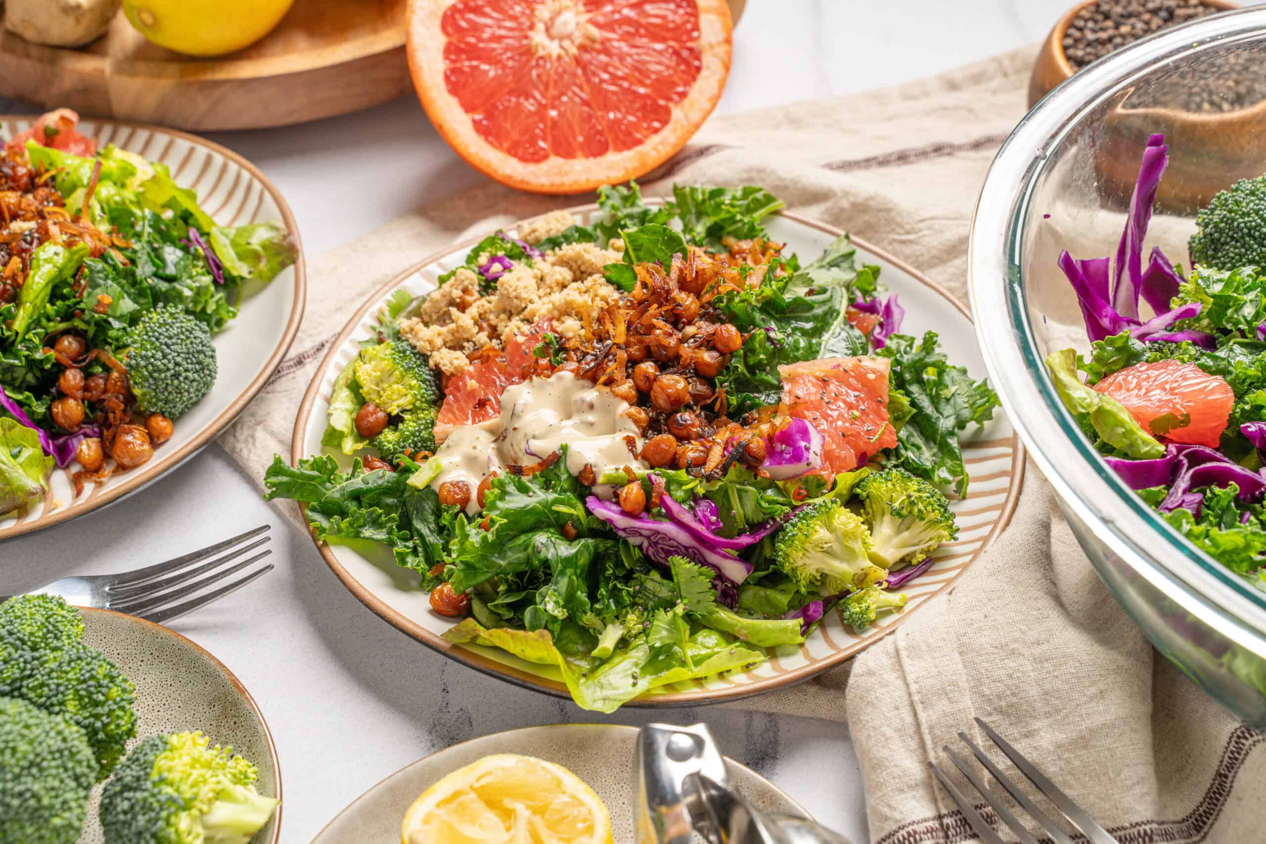 Fresh mixed salad with greens, roasted chickpeas, smoked salmon, cabbage, and creamy dressing on a white plate.
