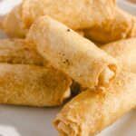 Deep-fried spring rolls served on a white plate, crispy golden exterior. Perfect appetizer or snack with a savory filling, ideal for parties or family dinners.