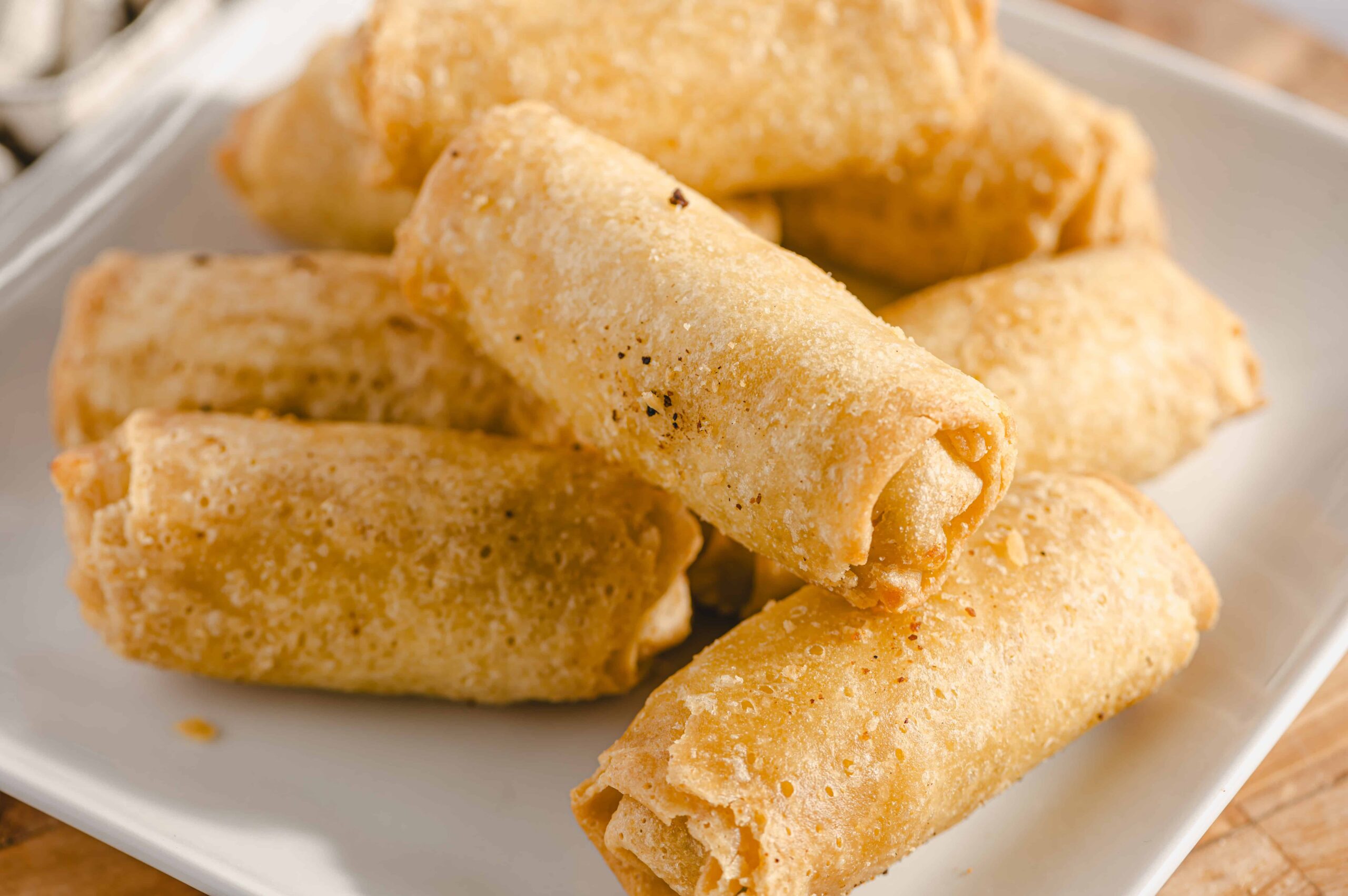 Deep-fried spring rolls served on a white plate, crispy golden exterior. Perfect appetizer or snack with a savory filling, ideal for parties or family dinners.