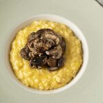 Creamy scrambled eggs topped with sautéed mushrooms served in a white bowl on a green plate, perfect for breakfast or brunch.