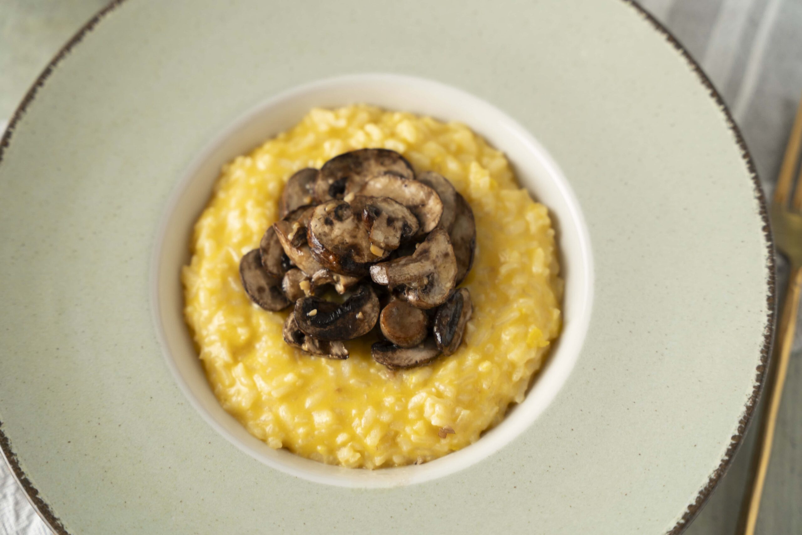 Creamy scrambled eggs topped with sautéed mushrooms served in a white bowl on a green plate, perfect for breakfast or brunch.