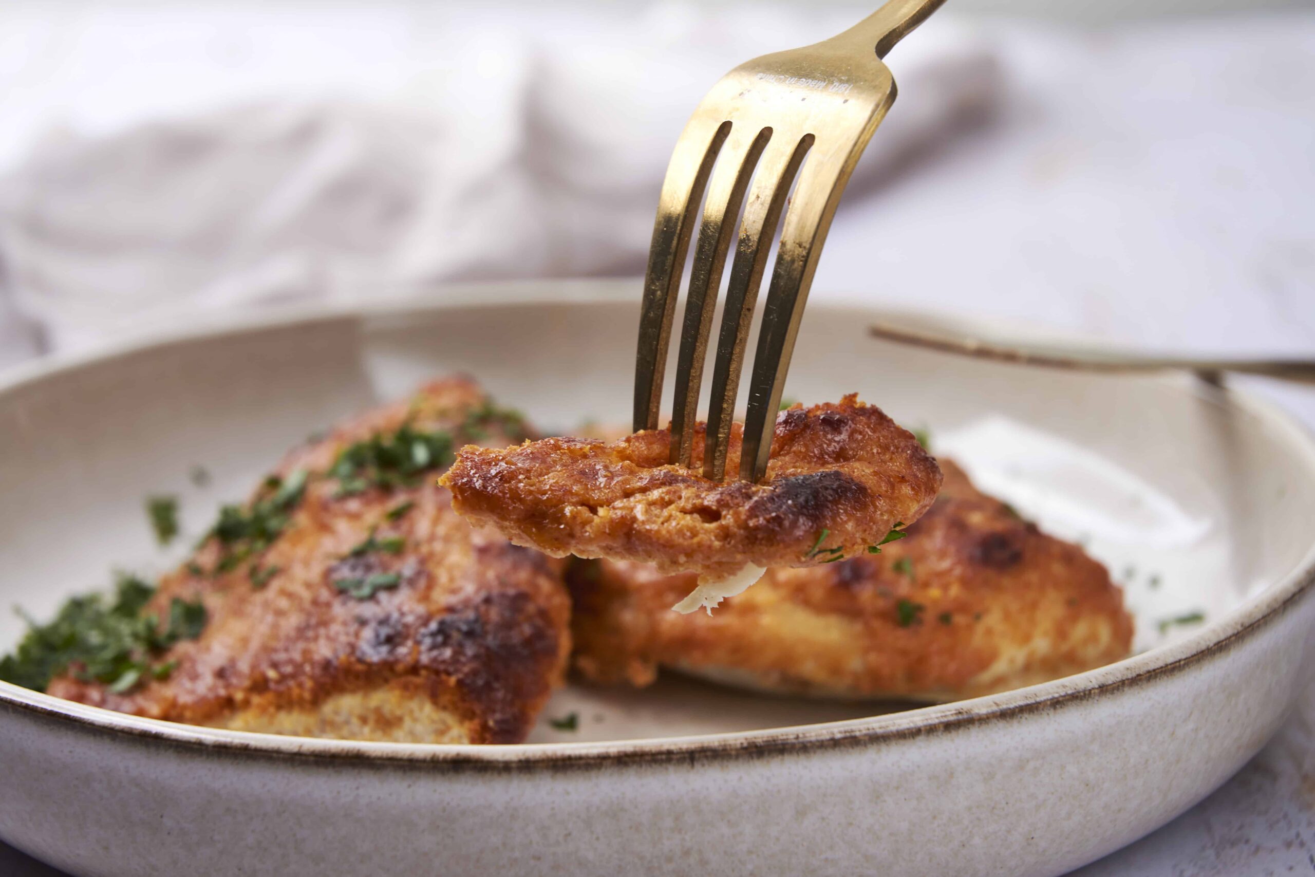 Crispy baked chicken thighs garnished with herbs on a white plate.