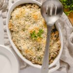 Creamy cheesy baked eggplant casserole garnished with fresh parsley in a white oval dish.