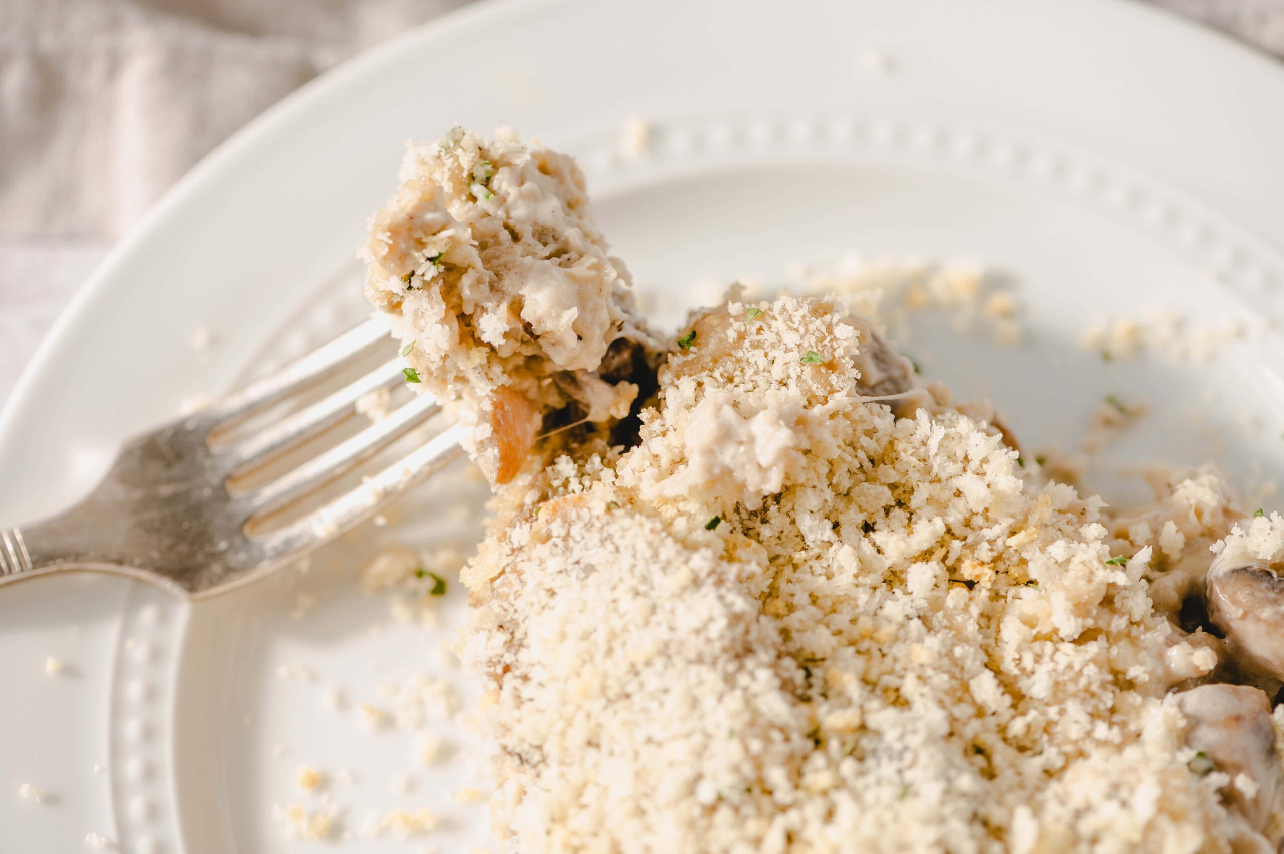 Creamy chicken casserole with a breadcrumb topping on a white plate, served with a fork, showcasing a comforting and delicious dish perfect for family dinners and easy weeknight meals.