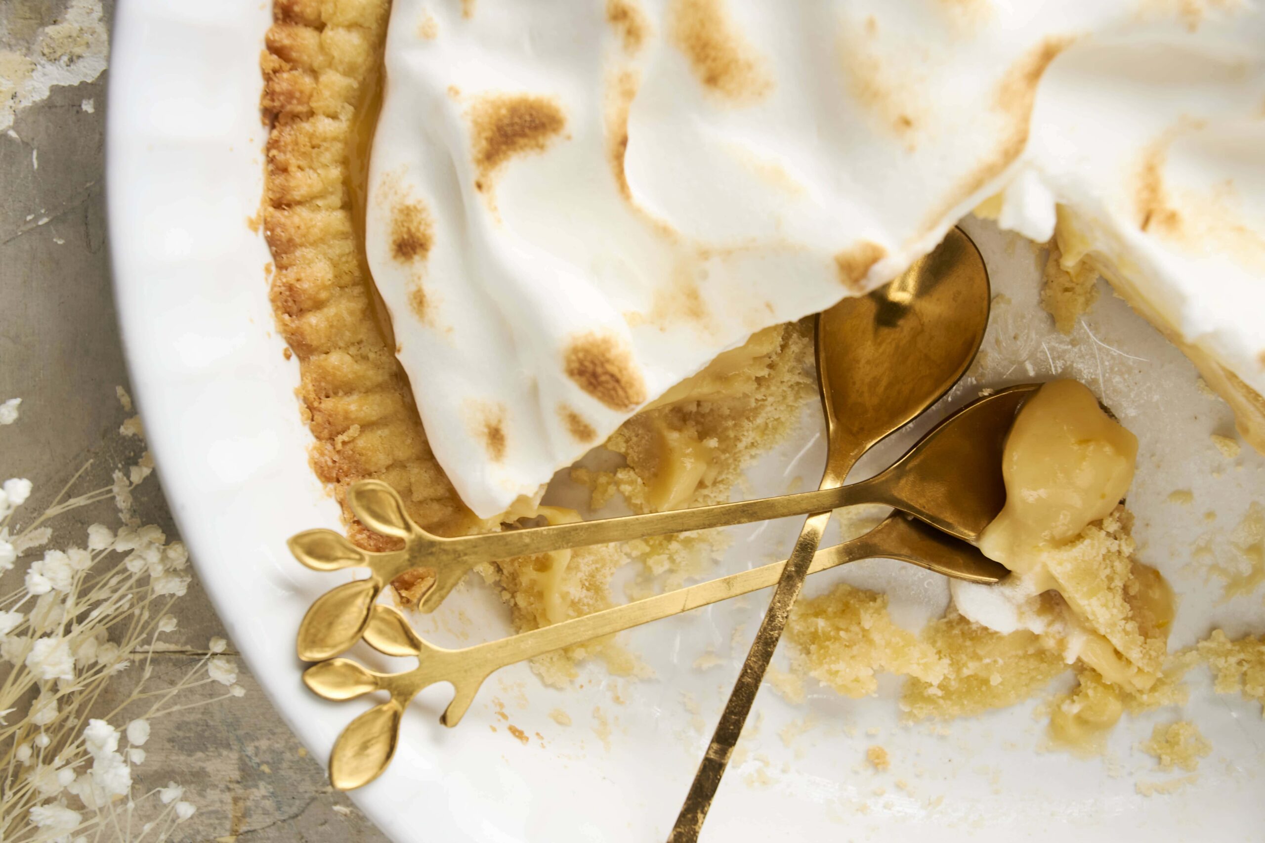 Creamy lemon meringue pie with golden toasted peaks on a white serving dish, with a slice removed revealing lemon filling and meringue topping. Perfect for dessert lovers and baking enthusiasts.