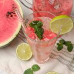 Refreshing watermelon lemonade with mint and lime, served over ice in a tall glass. Perfect summer drink made with fresh watermelon, lemon, and mint for a cool, fruity beverage.