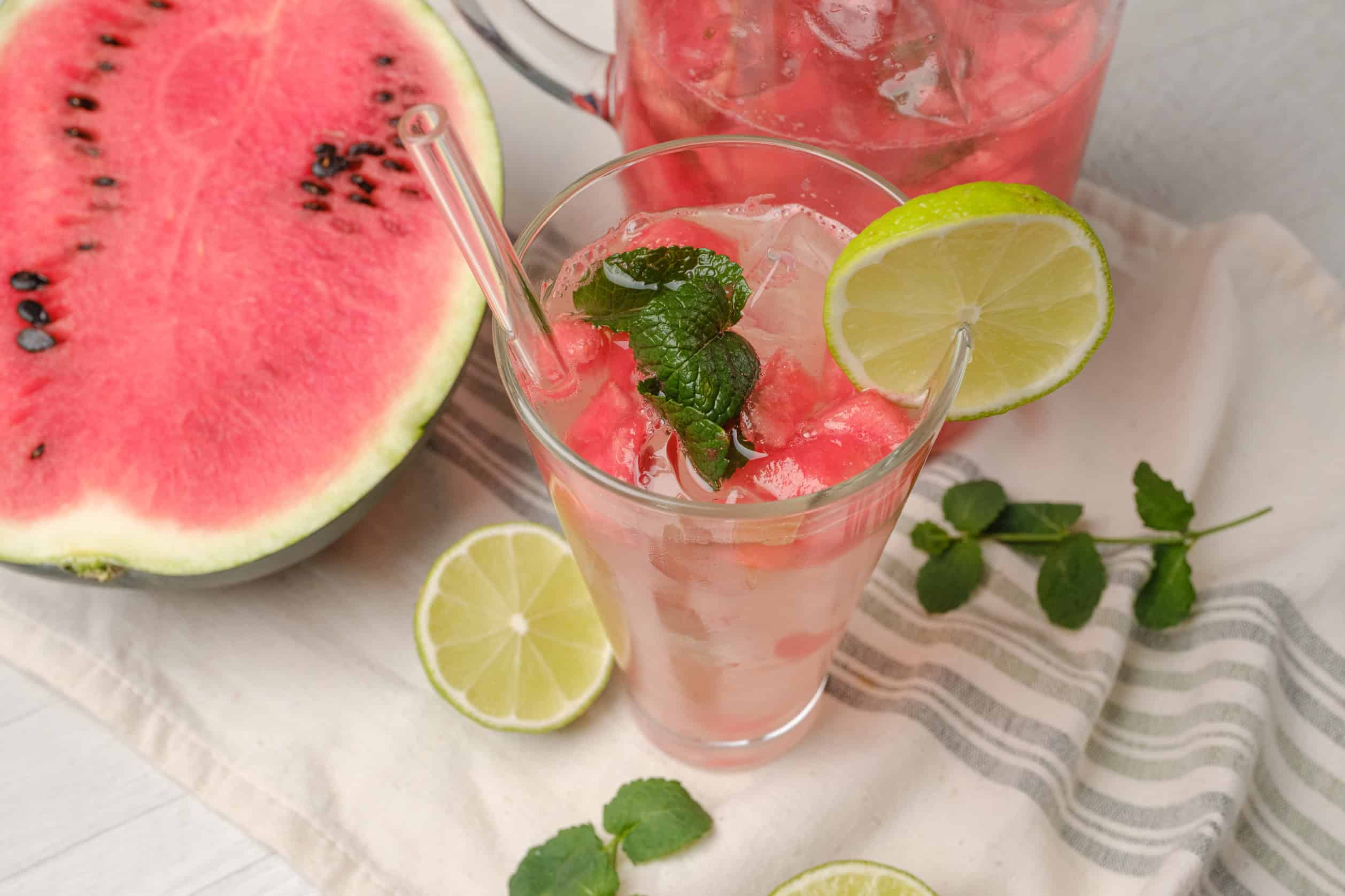 Refreshing watermelon lemonade with mint and lime, served over ice in a tall glass. Perfect summer drink made with fresh watermelon, lemon, and mint for a cool, fruity beverage.
