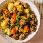 Juicy meatball and vegetable salad with potatoes, cherry tomatoes, zucchini, and fresh basil in a white honeycomb bowl, perfect for a healthy and flavorful meal.