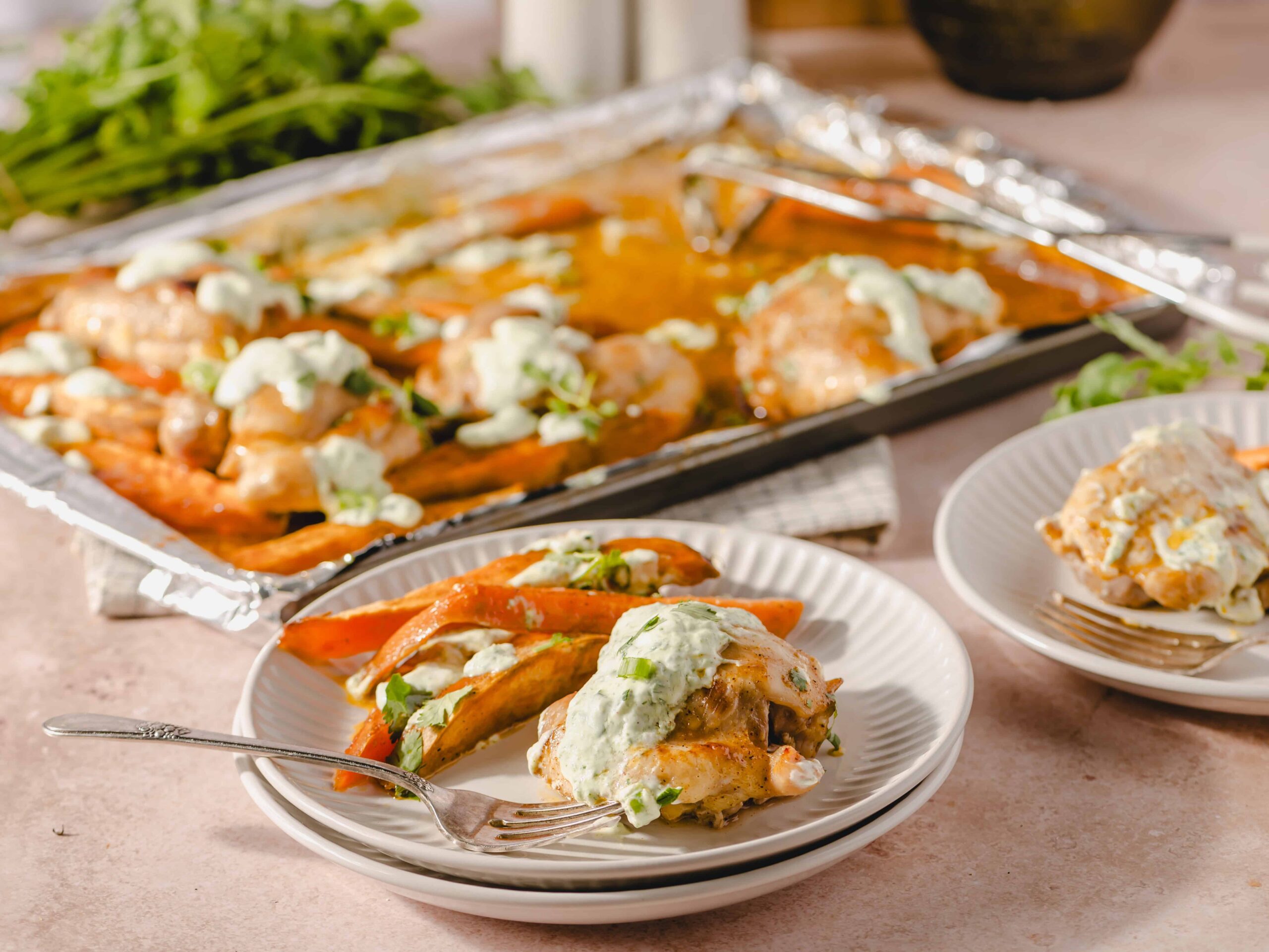 Roasted chicken with creamy herb sauce and roasted vegetables on a white plate. Baked chicken thighs served with a drizzle of herbed cream sauce, accompanied by roasted bell peppers, on a light pink surface.