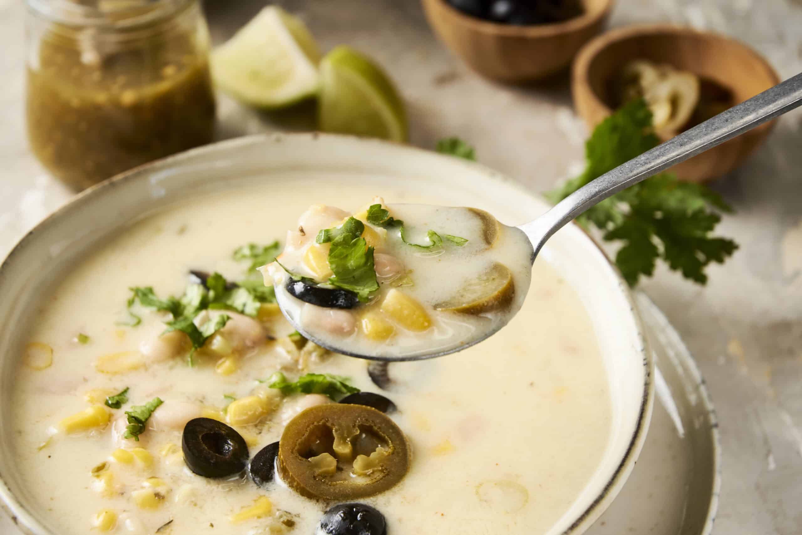 Creamy fish chowder with corn, black olives, sliced jalapeños, and fresh herbs in a rustic bowl. Perfect for seafood lovers, this comforting soup features a rich, flavorful broth with vibrant toppings.