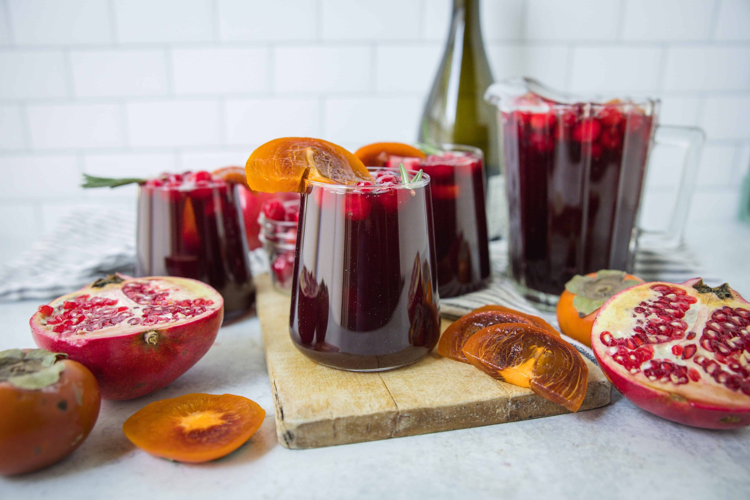 Vibrant homemade pomegranate and persimmon juice served in glasses with fresh fruit and ingredients on a rustic wooden board, perfect for healthy beverages and fruit recipes.