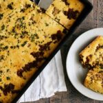 Golden baked dish with beef, cheese, and herbs in a black baking dish.