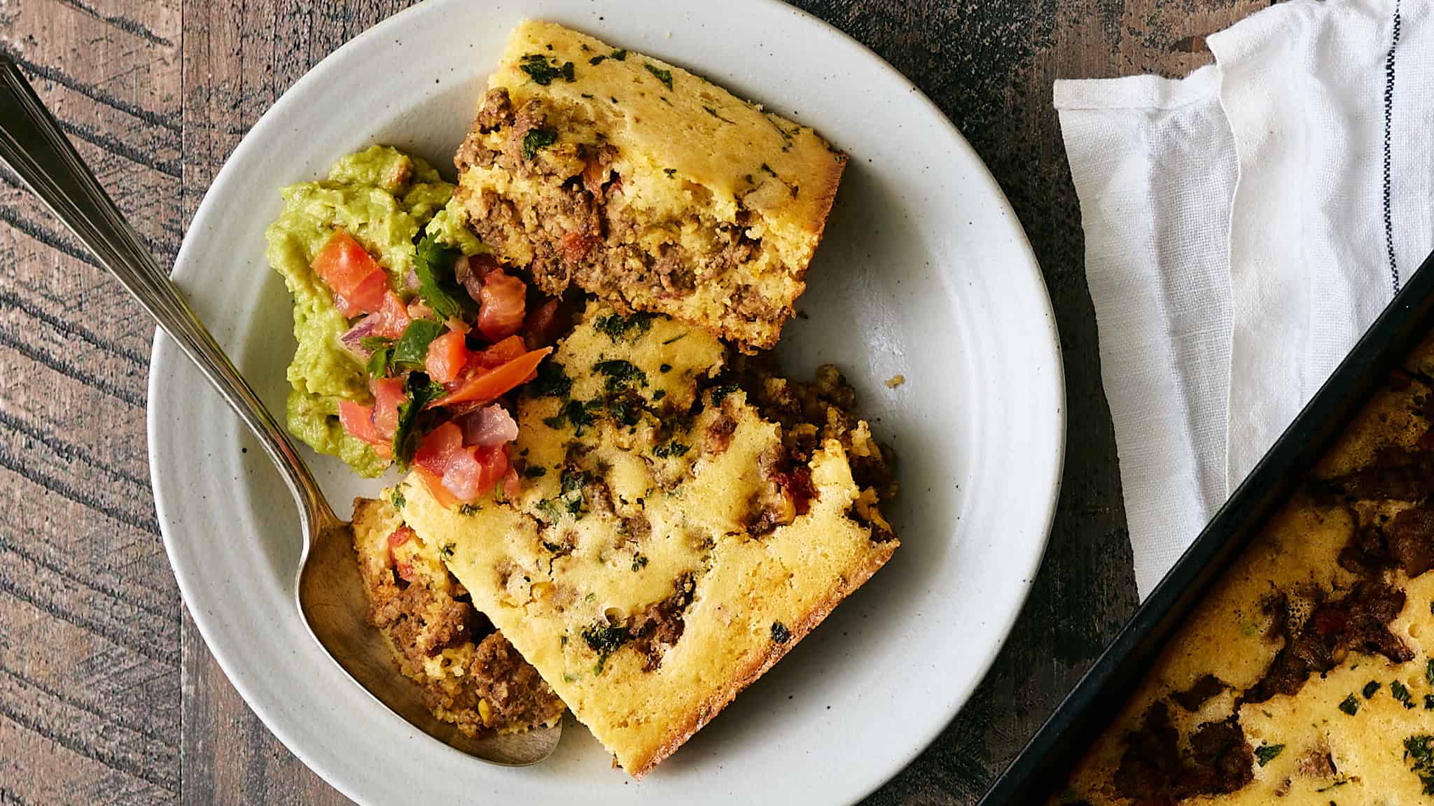 Savory baked casserole with ground beef, potatoes, and herbs served with fresh guacamole and pico de gallo. Perfect comfort food for family dinners or casual gatherings.