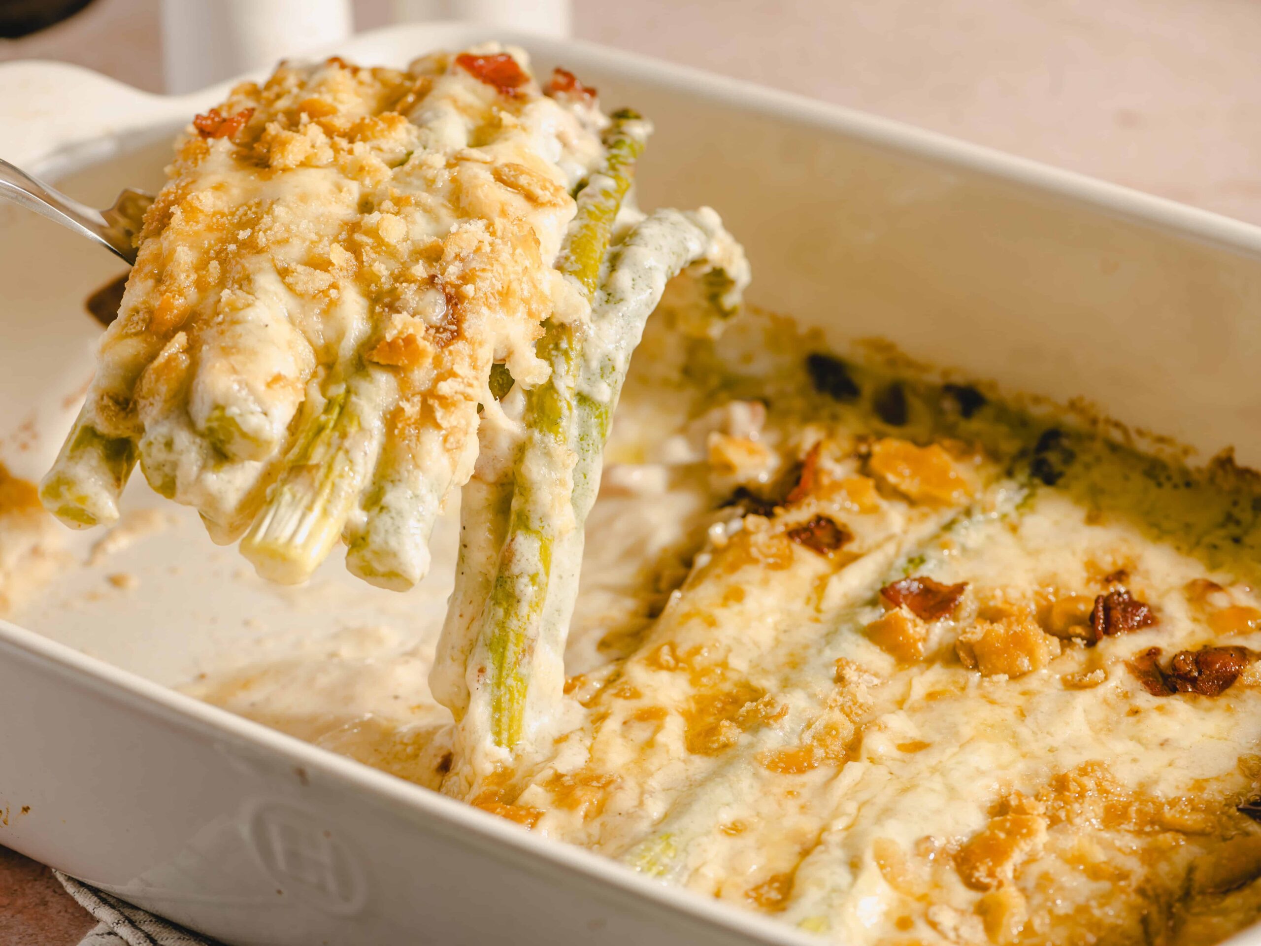 Creamy baked green bean casserole topped with crispy fried onions, served in a white baking dish, showcasing a classic comfort food dish perfect for holidays and family dinners.