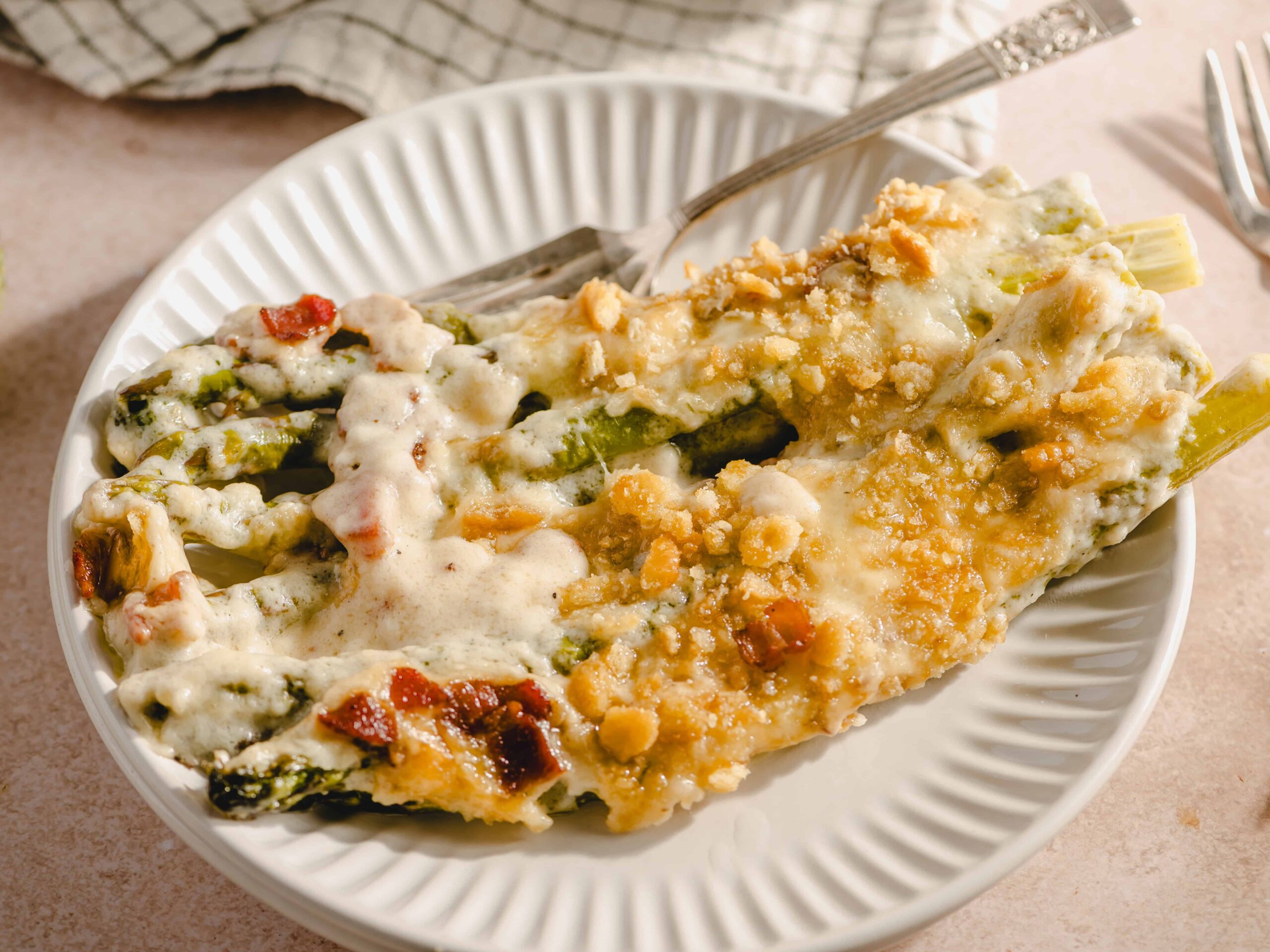 Baked green bean casserole with crispy fried onion topping on a white plate, savory comfort food for holidays or family dinners.
