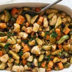 Oven-roasted vegetable medley with Brussels sprouts, sweet potatoes, cauliflower, and herbs in a white baking dish. Perfect healthy side dish for dinner or meal prep.