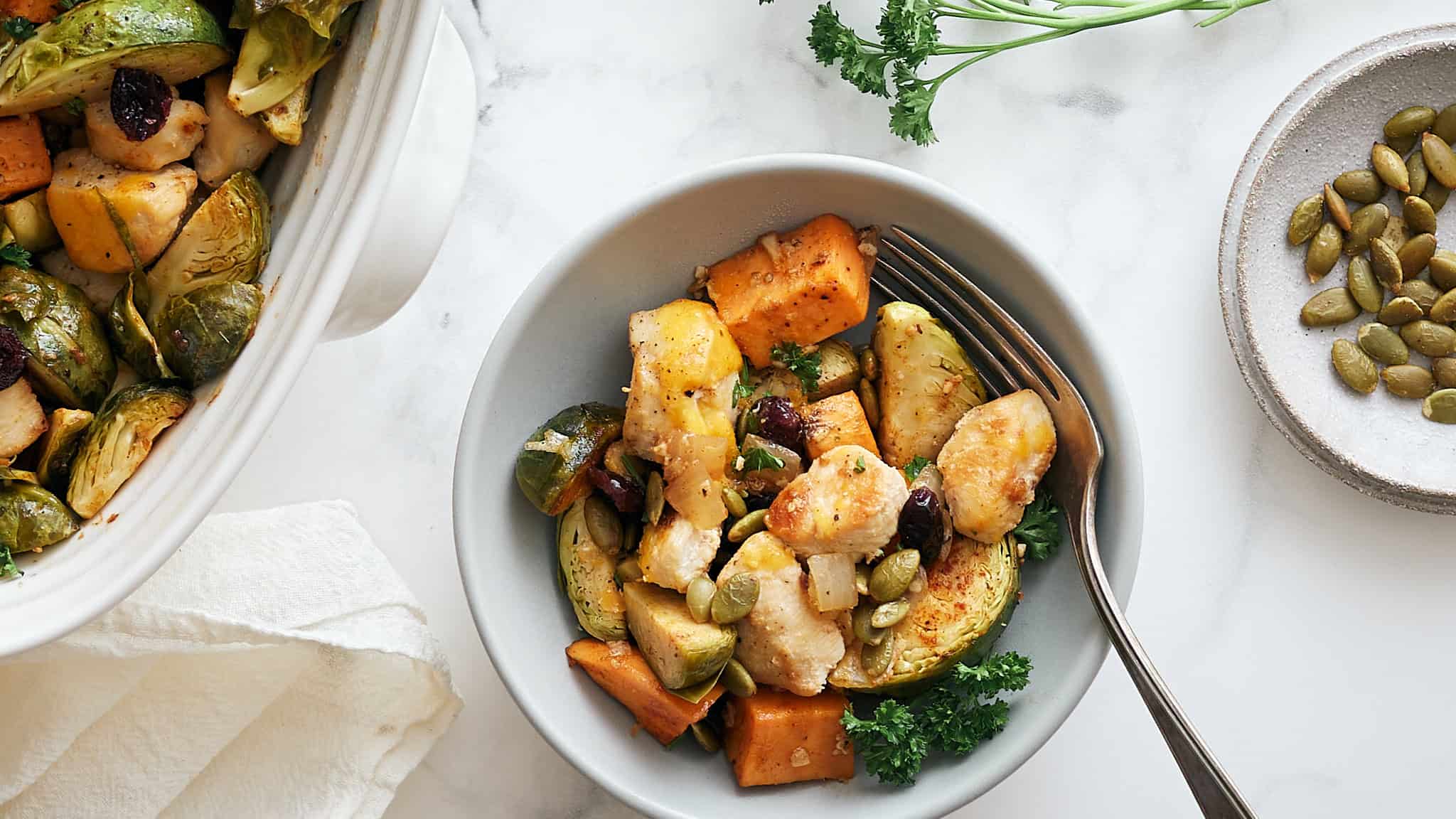 Roasted vegetable chicken casserole served with pumpkin, sweet potatoes, zucchini, and kale, topped with pumpkin seeds and fresh parsley for a healthy and delicious meal.