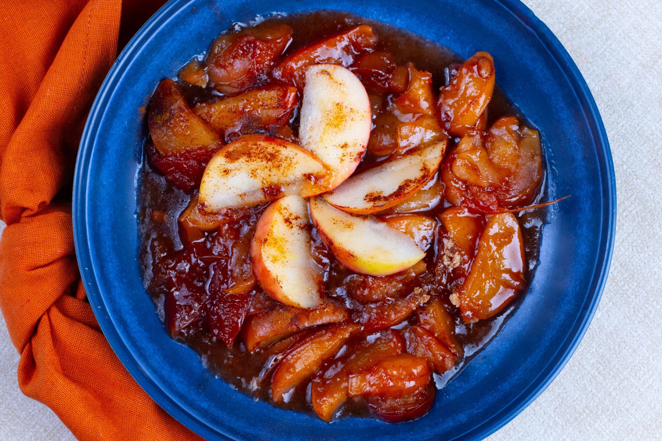 Soft poached pears in a rich caramel sauce served on a blue plate. Perfect for dessert or a sweet snack, easy to make with fresh pears and sweetened caramel.