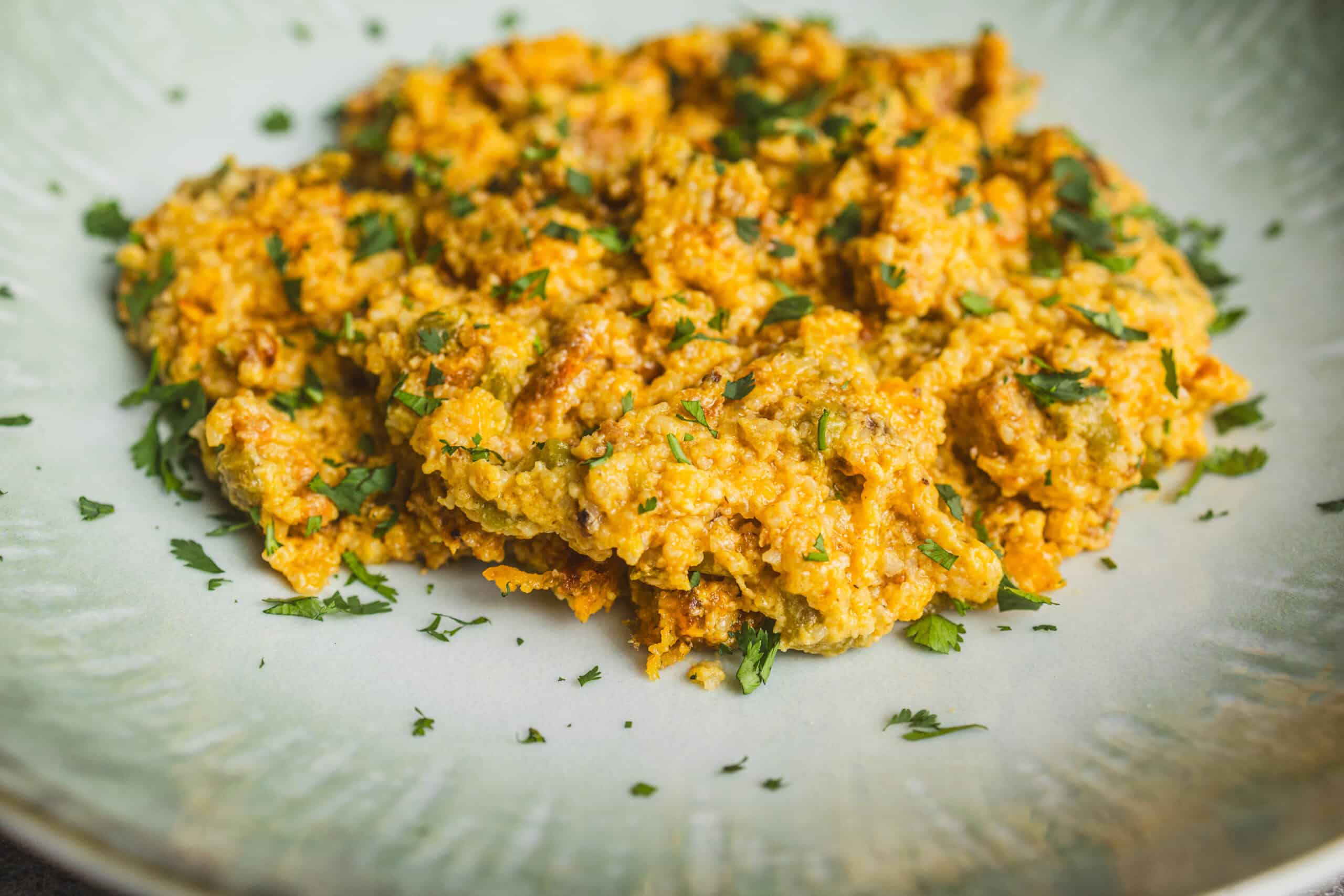 Creamy scrambled eggs with vegetables garnished with chopped cilantro, served on a light-colored plate. Perfect for breakfast or brunch, healthy and flavorful egg scramble with herbs and vegetables.