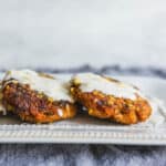 Crispy fried chicken cutlets topped with creamy white sauce, served on an elegant white plate with a dark textured background. Perfect for comfort food recipes and meal ideas.