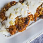 Crispy fried chicken fillet topped with creamy white sauce and chopped nuts, served on a white dish. Perfect comfort food recipe with rich flavors and crunchy texture.