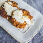 Crispy breaded chicken fried steak topped with creamy white gravy and sprinkled with lemon zest on a white decorative plate.