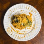 Crab spinach gratin with golden breadcrumb topping on white plate, served on wooden table, delicious seafood dish, easy recipe, healthy spinach and crab mix.
