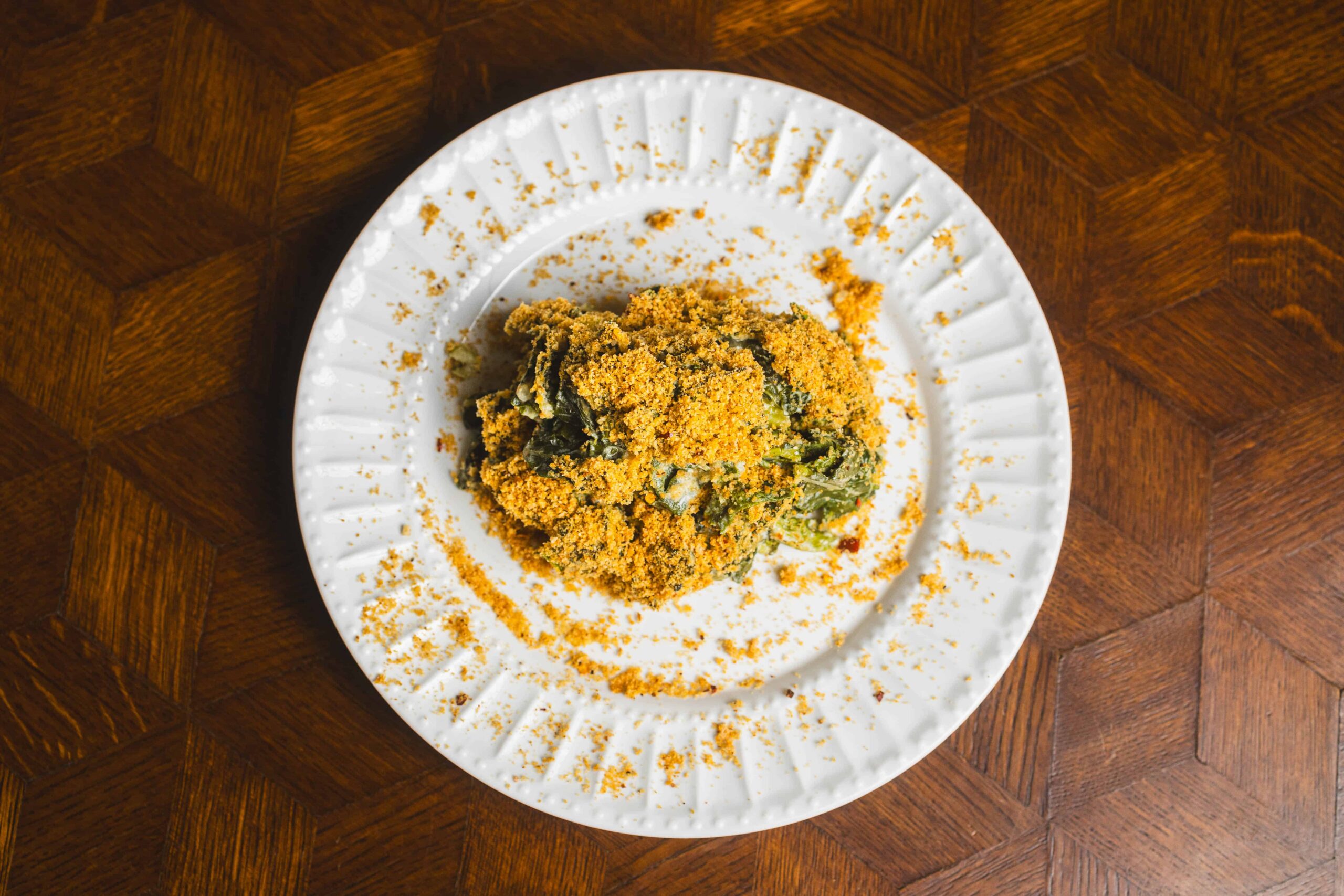 Crab spinach gratin with golden breadcrumb topping on white plate, served on wooden table, delicious seafood dish, easy recipe, healthy spinach and crab mix.