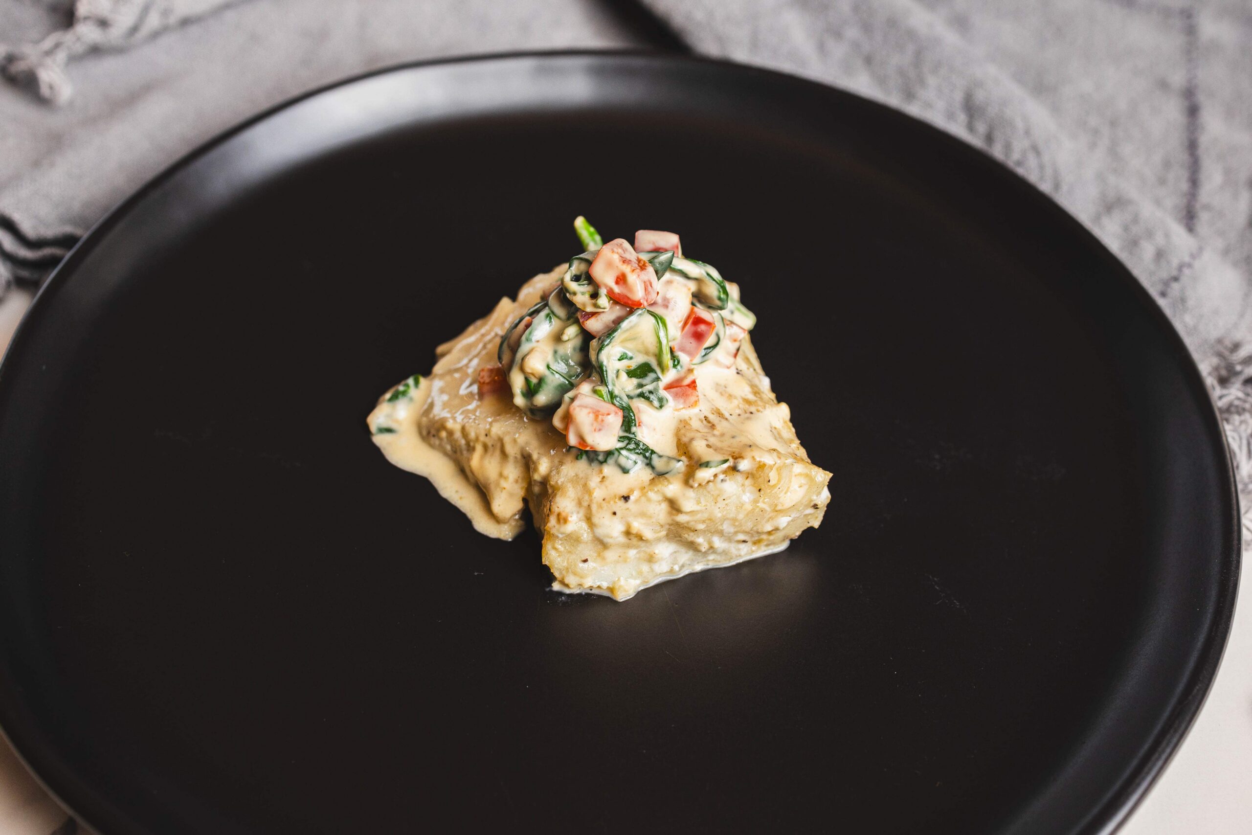 Creamy baked potato topped with fresh vegetable salad on a black plate, perfect for comfort food or dinner recipes.