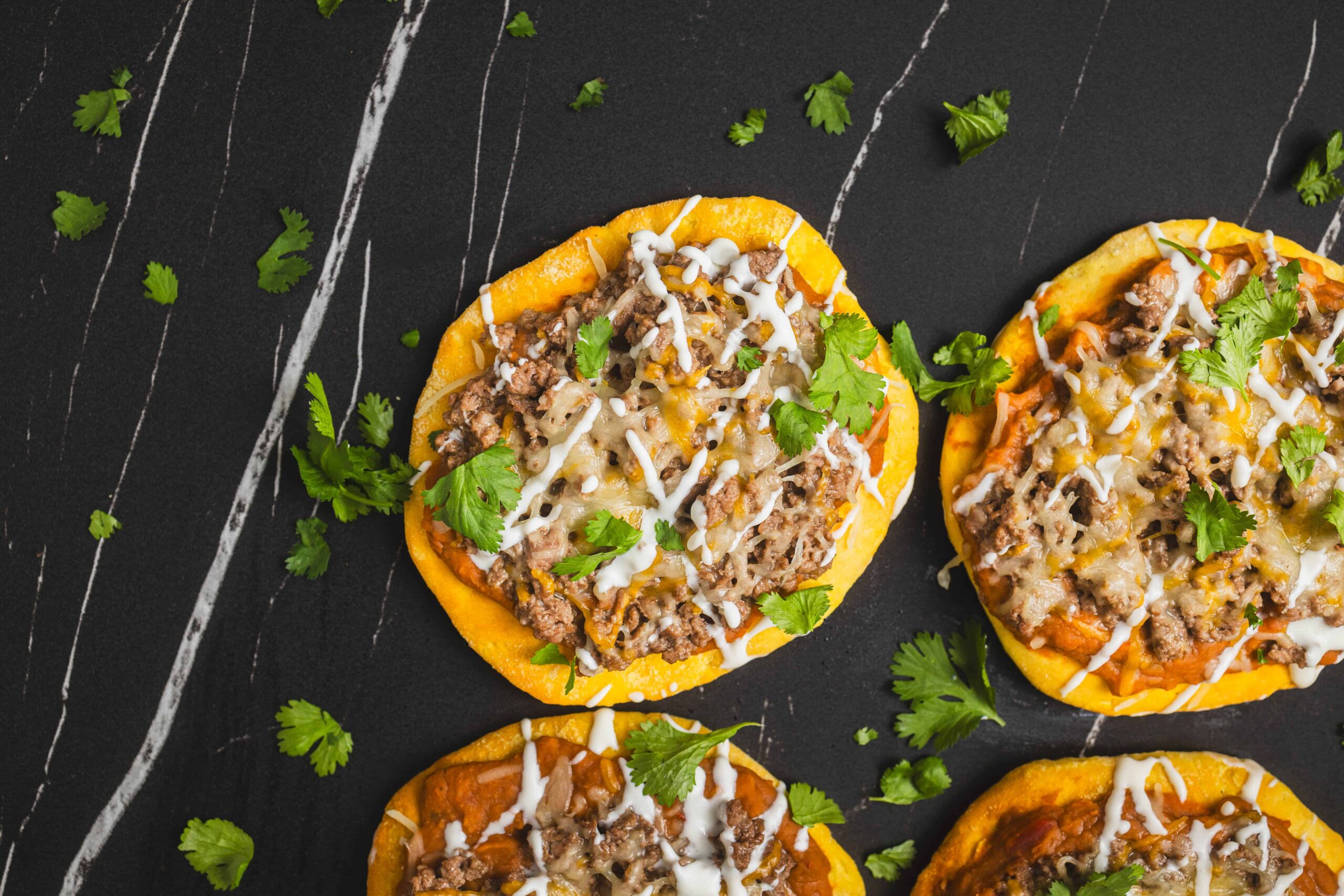 Savory taco ingredients inside crispy corn tortillas topped with cheese and fresh cilantro. Perfect for easy homemade tacos, meal prep, or taco night, featuring seasoned ground beef and melted cheese on a dark background.