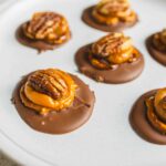 Sweet chocolate peanut butter cups with caramel on a white plate, close-up image.