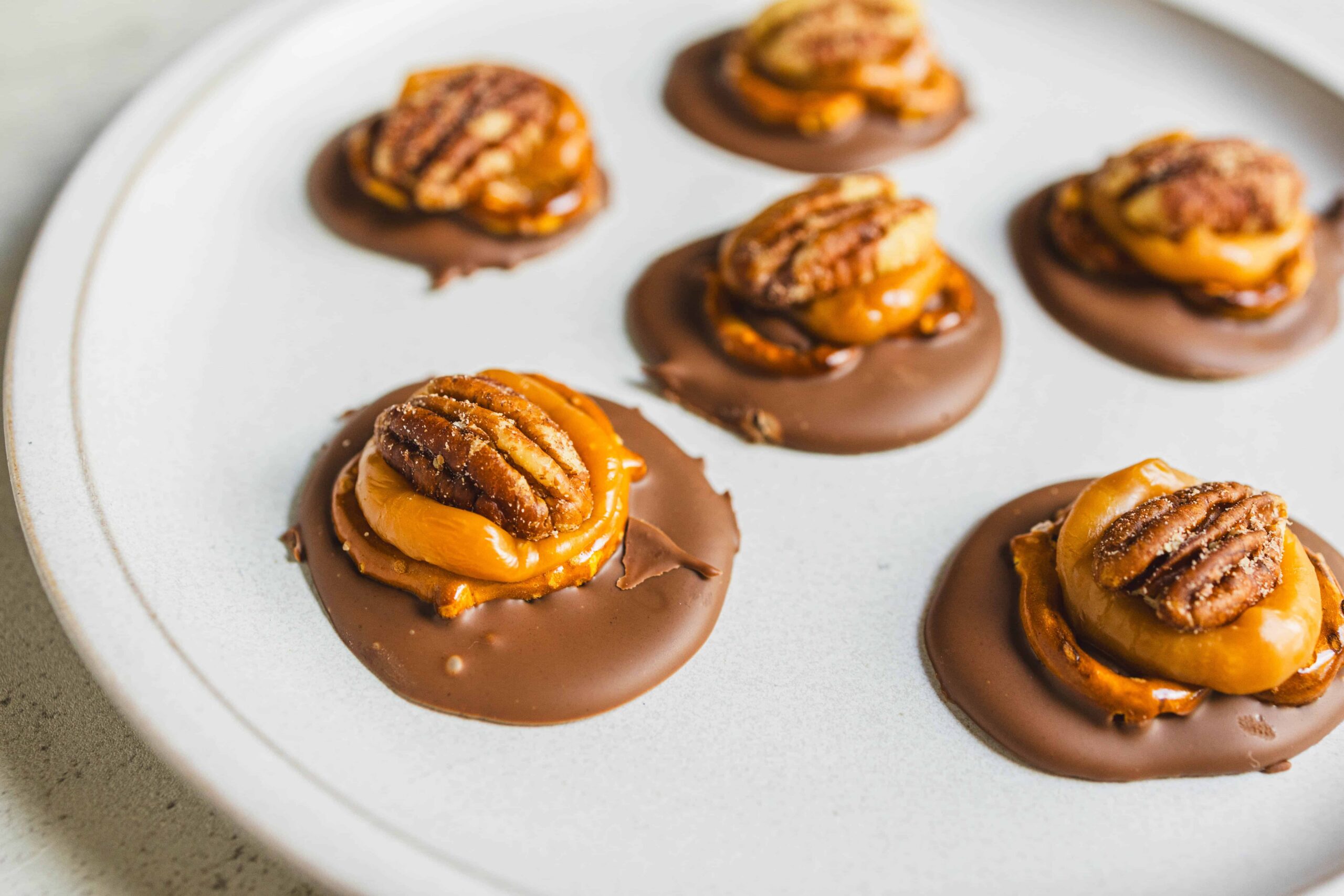 Sweet chocolate peanut butter cups with caramel on a white plate, close-up image.