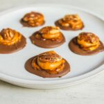 Peanut butter cup pretzel bites with caramel and pecans on a white plate, perfect for snack recipes and quick desserts.