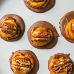 Decadent caramel and pecan chocolate cups topped with pecan halves, perfect for holiday desserts and sweet treats. Visually appealing, rich, and indulgent, ideal for chocolate lovers.