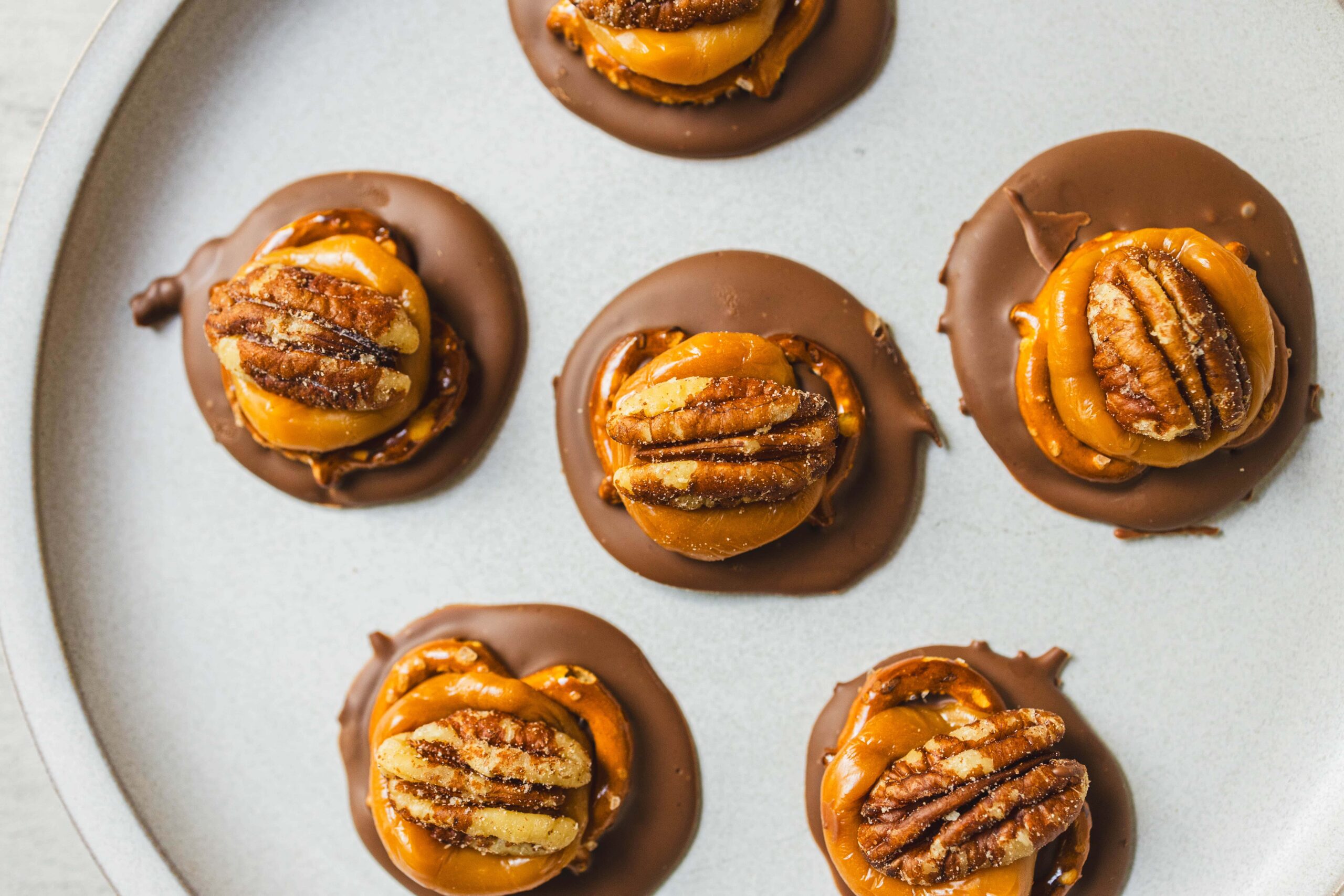 Decadent caramel and pecan chocolate cups topped with pecan halves, perfect for holiday desserts and sweet treats. Visually appealing, rich, and indulgent, ideal for chocolate lovers.